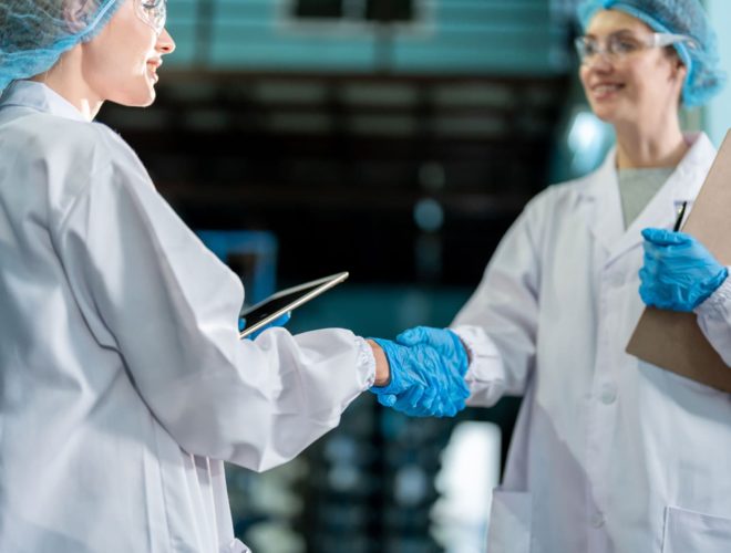 Two food factory workers shake hands after completing food factory training