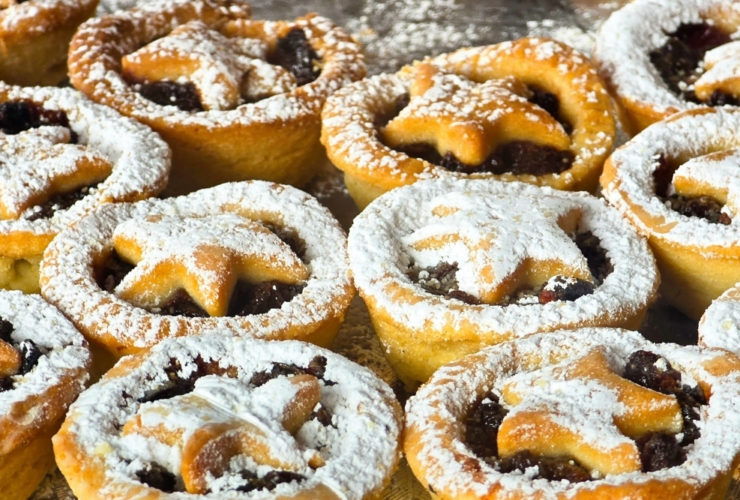 Mince pies dusted with icing sugar sit in neat rows, reflecting seasonal food manufacturing in the UK.