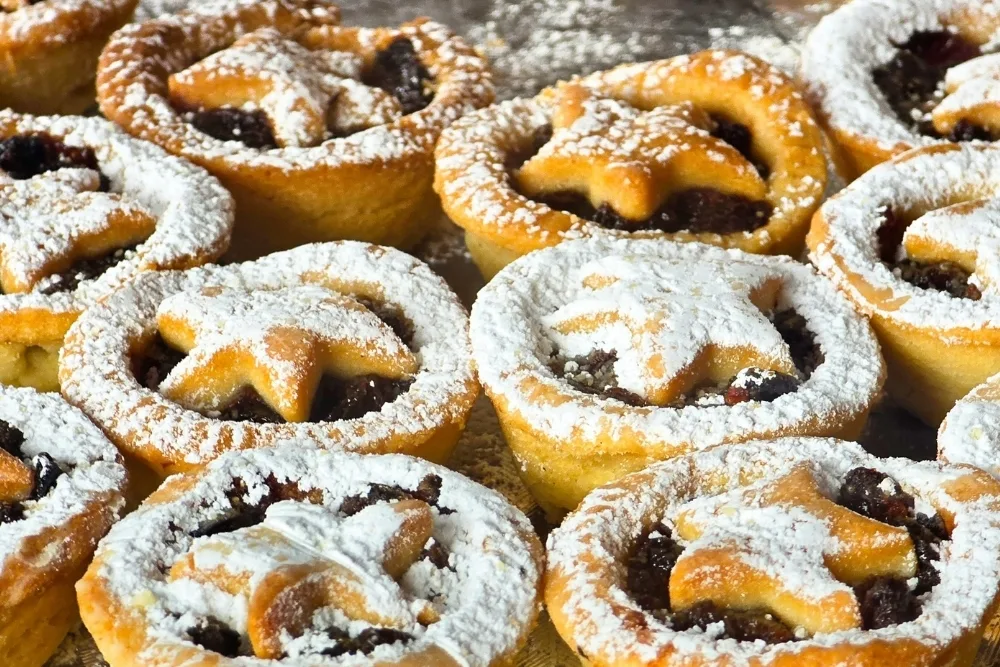 Mince pies dusted with icing sugar sit in neat rows, reflecting seasonal food manufacturing in the UK.