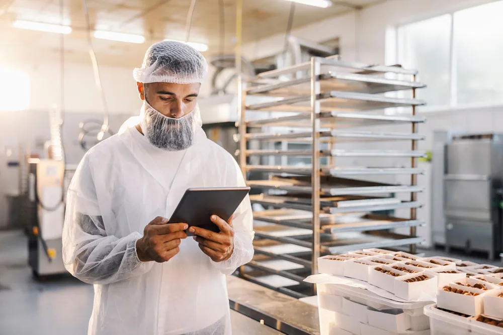 Food factory worker completing food factory training on a tablet in a food factory.